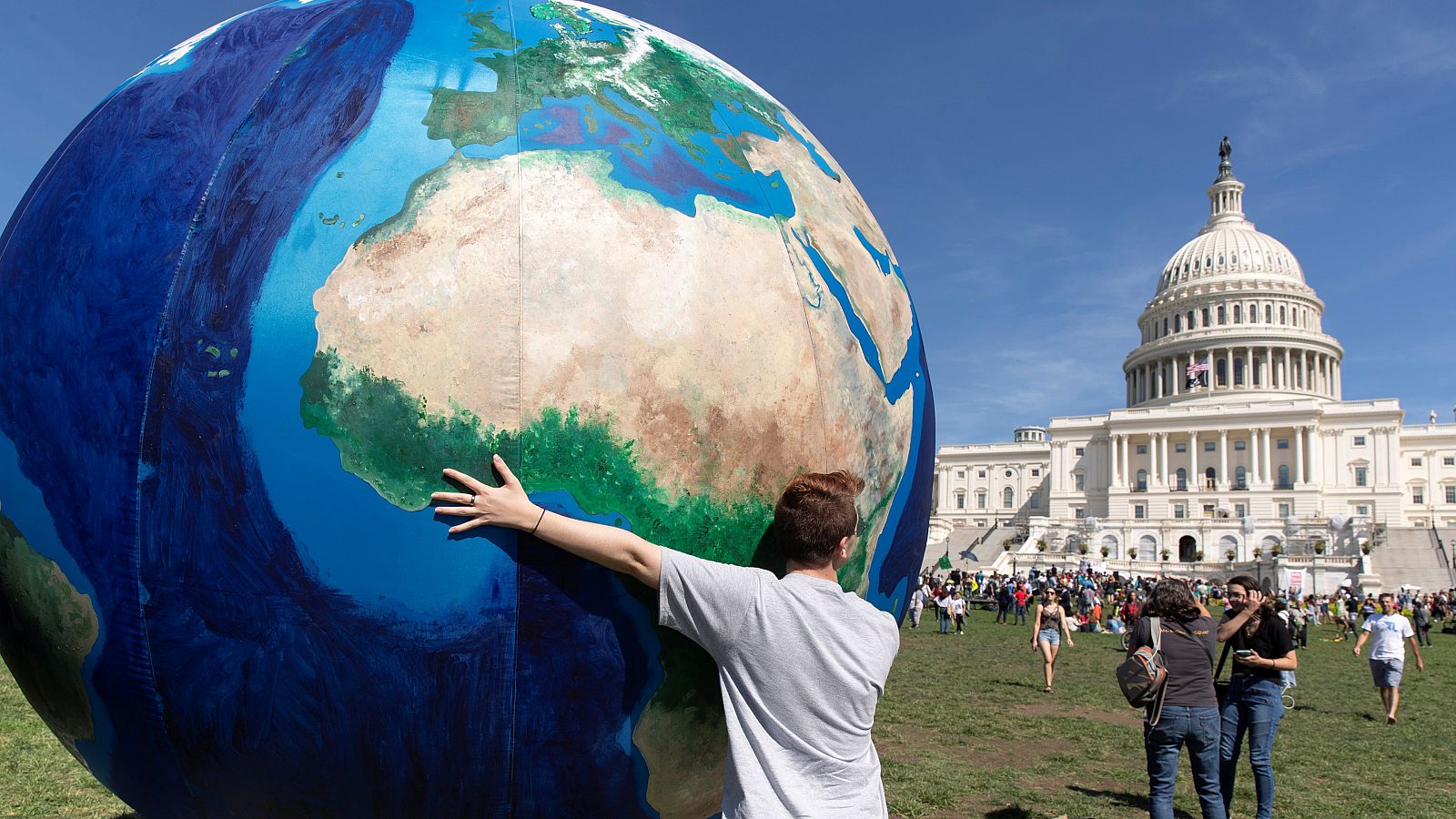Un joven sostiene un globo terráqueo gigante frente al Capitolio de EE.UU. para protestar contra el cambio climático.