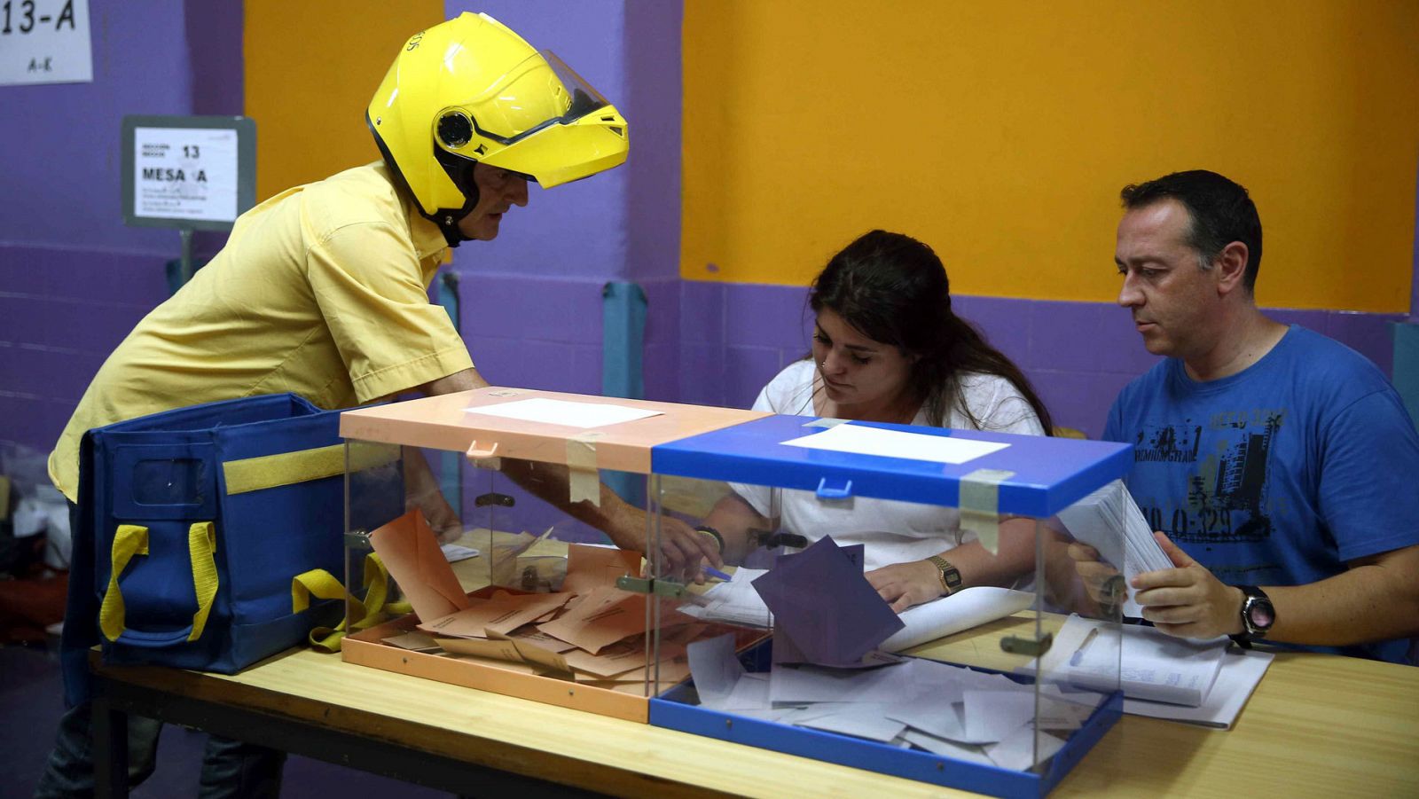 Un cartero entrega el voto por correo en una de las mesas electorales de un colegio de l'Hospitalet de Llobregat.