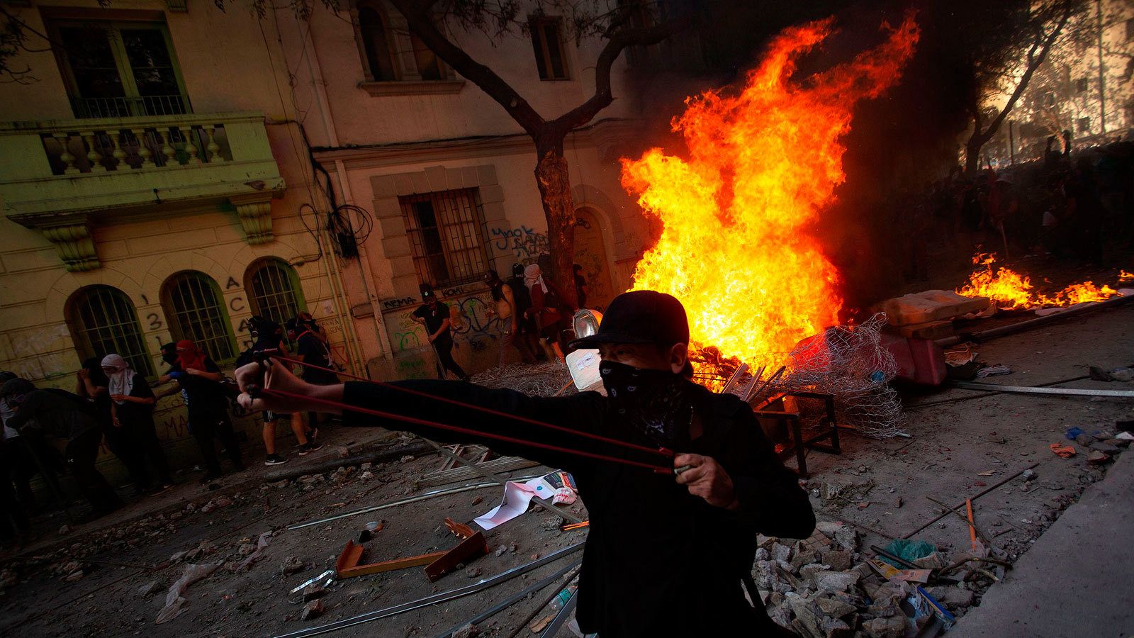 Varios manifestantes encapuchados se enfrentan a las fuerzas de seguridad en una barricada en Santiago de Chile