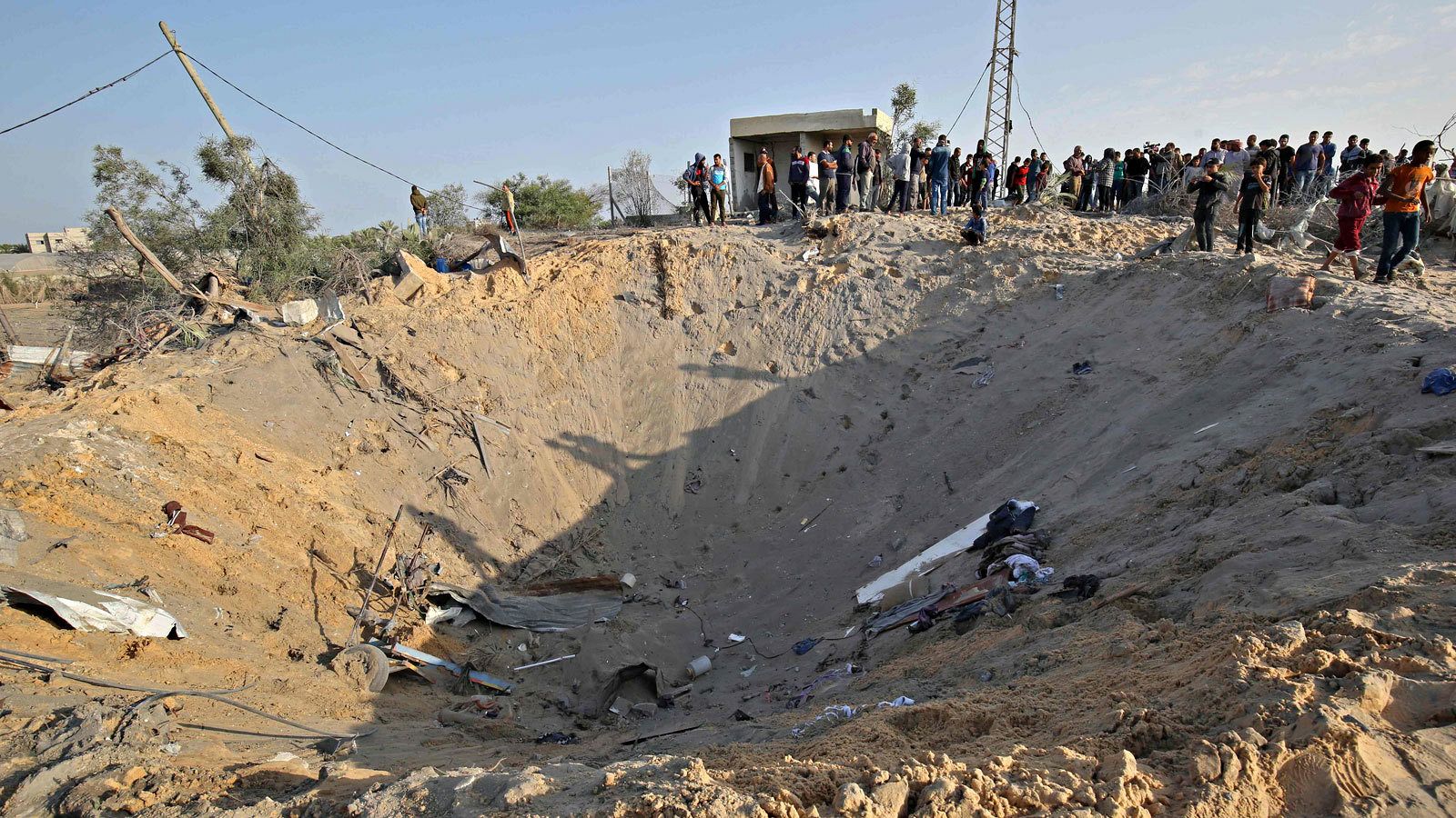 Los palestinos observan el cráter dejado por un proyectil israelí en Deir al Balah, en el sur de la Franja de Gaza