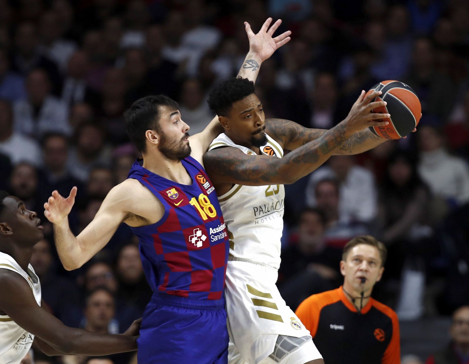 El pívot estadounidense del Real Madrid Jordan Mickey (d) lucha un balón con el ala-pívot del Barcelona Pierre Oriola (i)