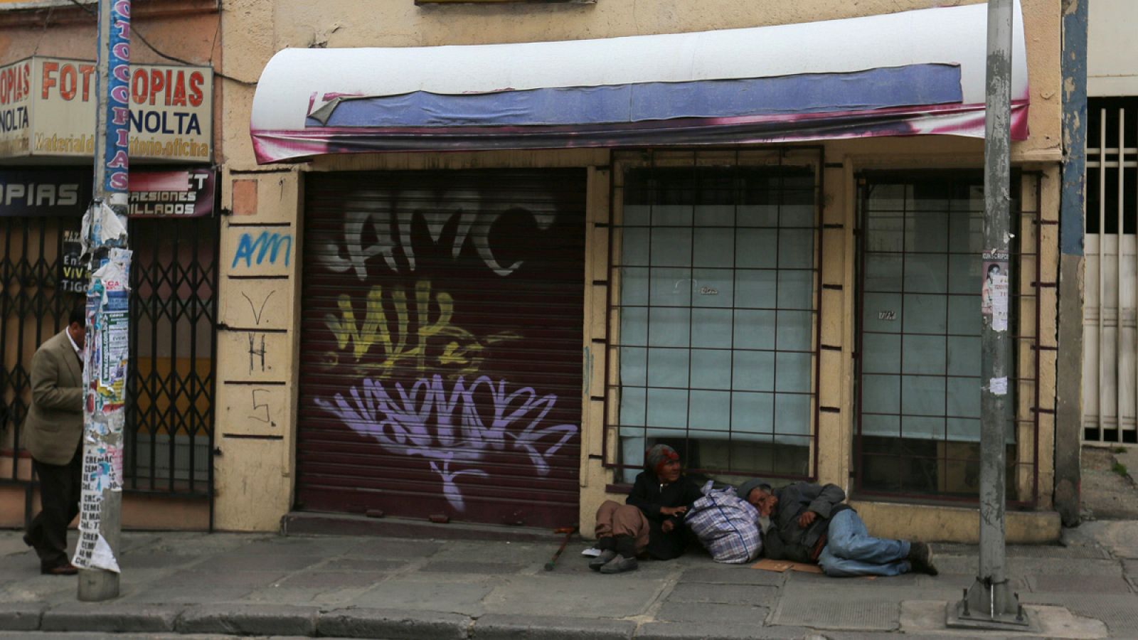 Dos personas duermen en la acera, frente a comercios cerrados en La Paz, Bolivia
