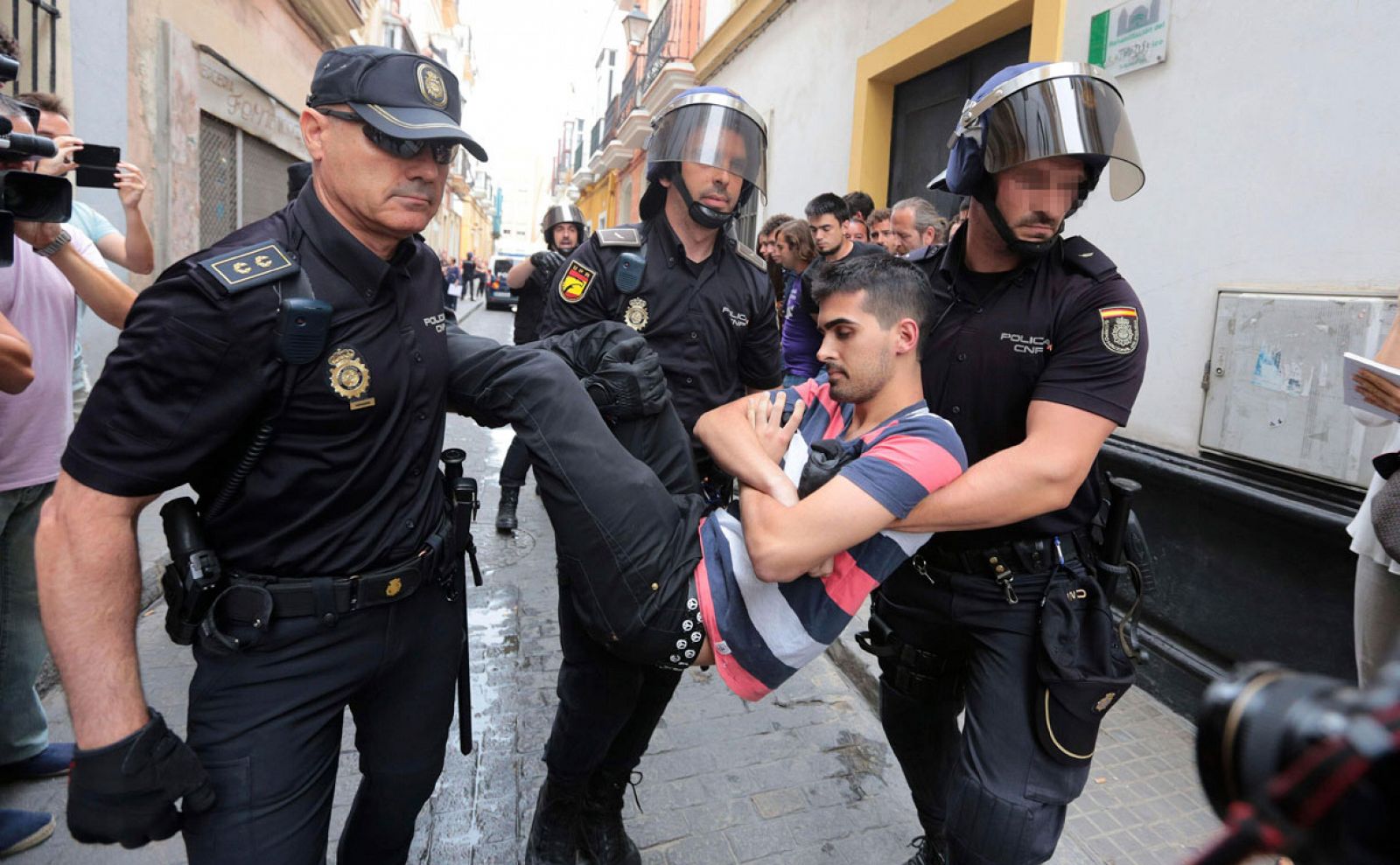 Agentes de la Policía Nacional llevan a una de las personas que intentaban evitar un desahucio a una familia que vivía en su casa de Cádiz en régimen de alquiler pero que finalmente fue desalojada en 2015 por una orden judicial.