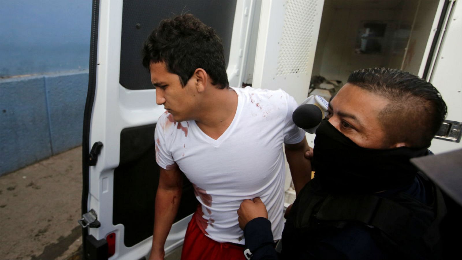 Un policía escolta a un preso herido en la cárcel de El Porvenir (Honduras).