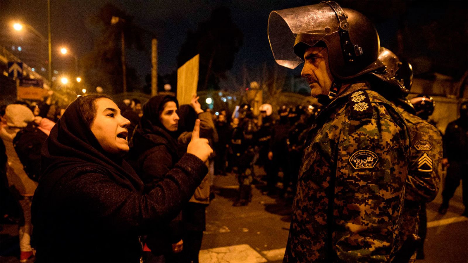 Una mujer habla a un agente iraní en un vigilia en Teherán por las víctimas del avión derribado