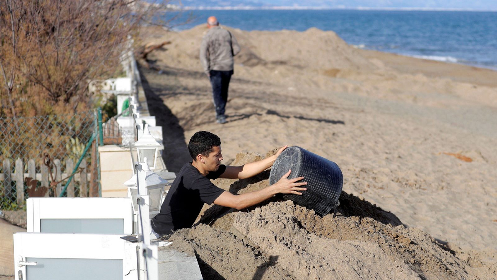 Un hombre retira la arena que el temporal Gloria ha acumulado ante su vivienda