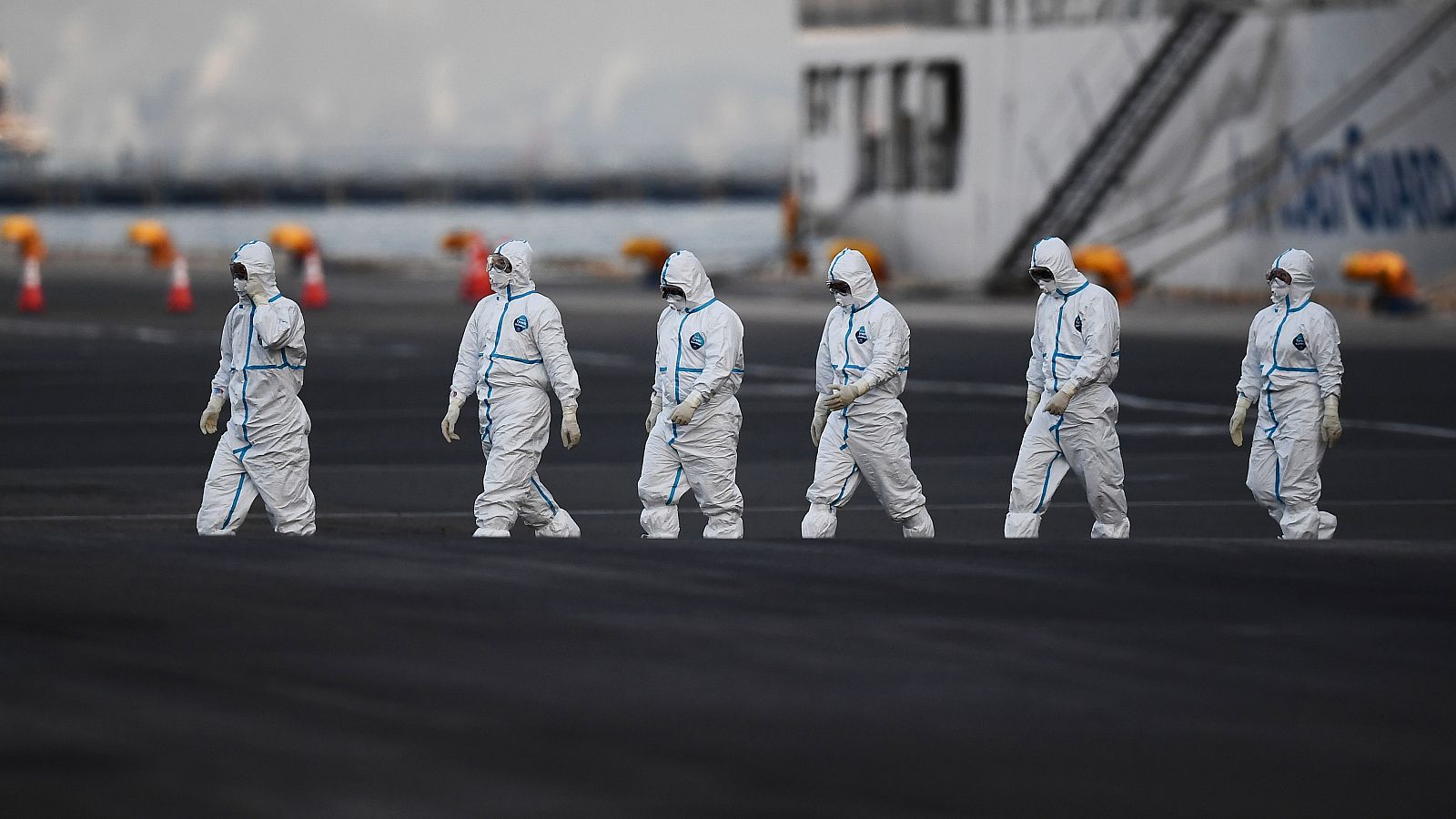 Trabajadores con trajes protectores se alejan del crucero japonés Diamond Princess, donde se han registrado al menos 130 contagios.