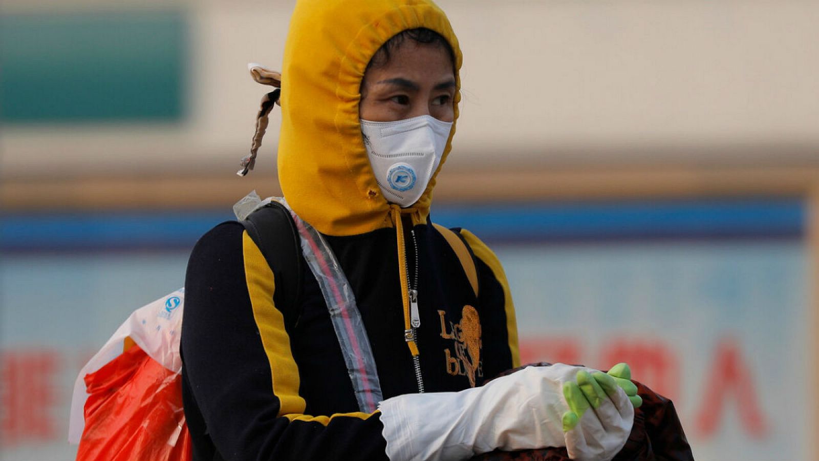 Cerca de la estación de tren de Pekín, una mujer se protege con mascarilla y guantes ante el coronavirus.