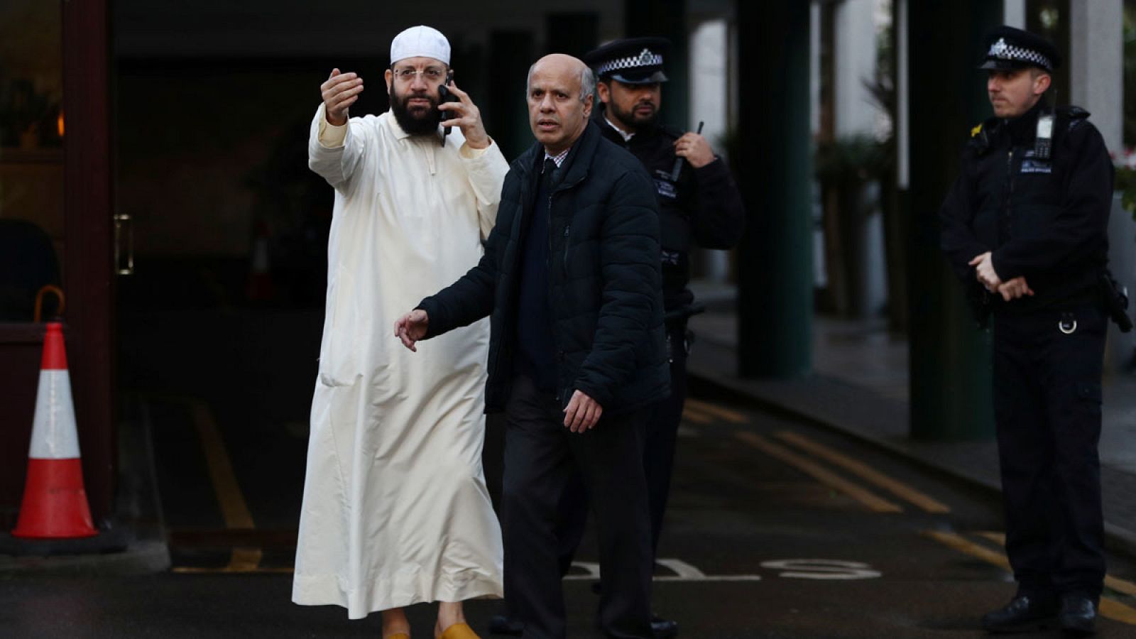 Un hombre habla con los agentes de la policía británica a las puertas de la mezquita central de Londres.