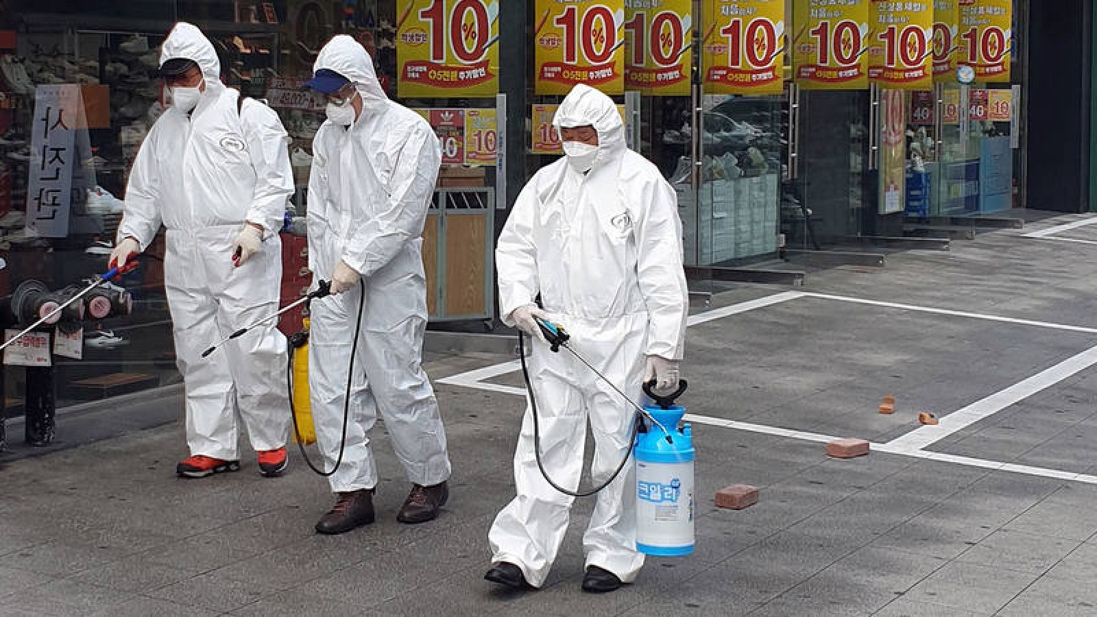 Empleados de una empresa de servicios de desinfección desinfectando una calle en Daejeon, Corea del Sur.
