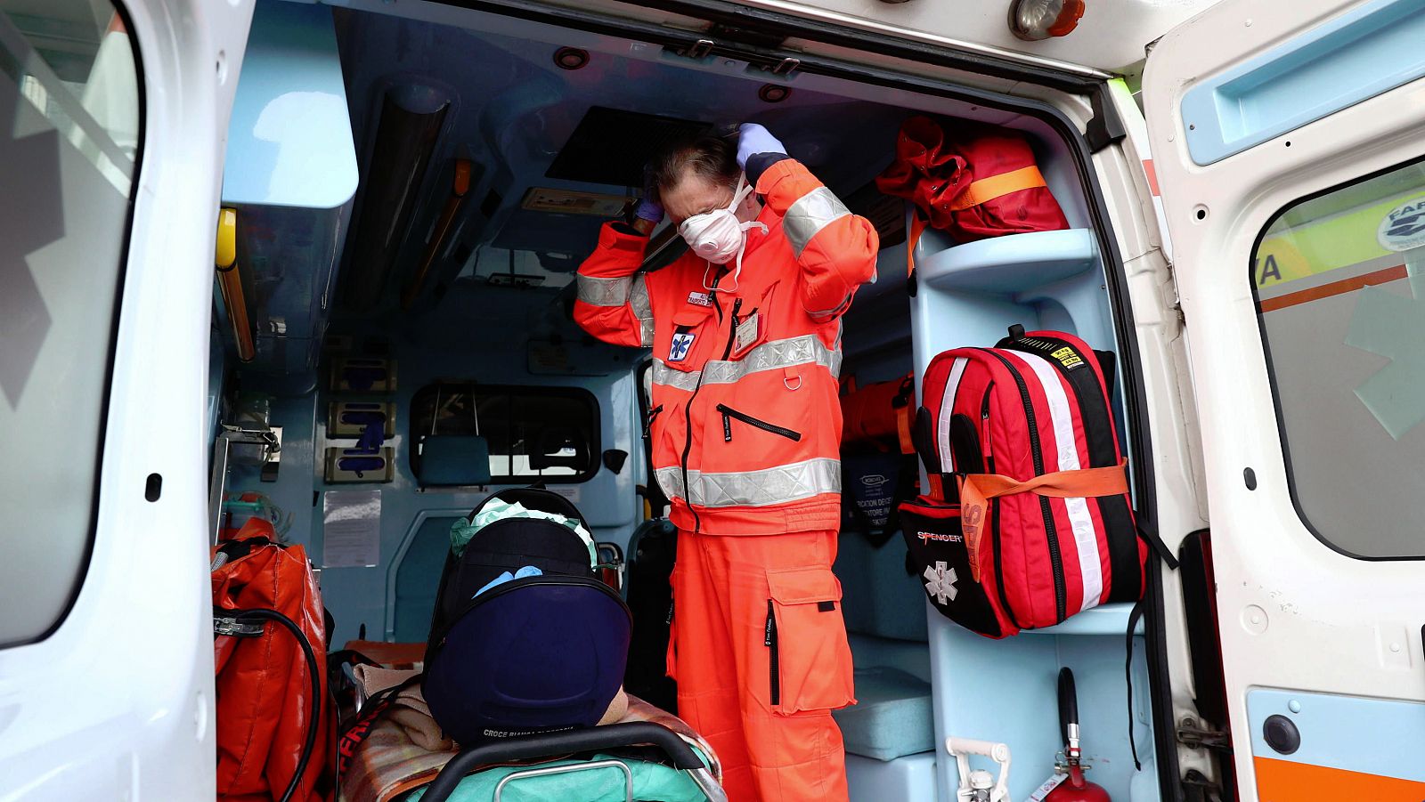 Un trabajador sanitario italiano se coloca una máscara de protección en una ambulancia.