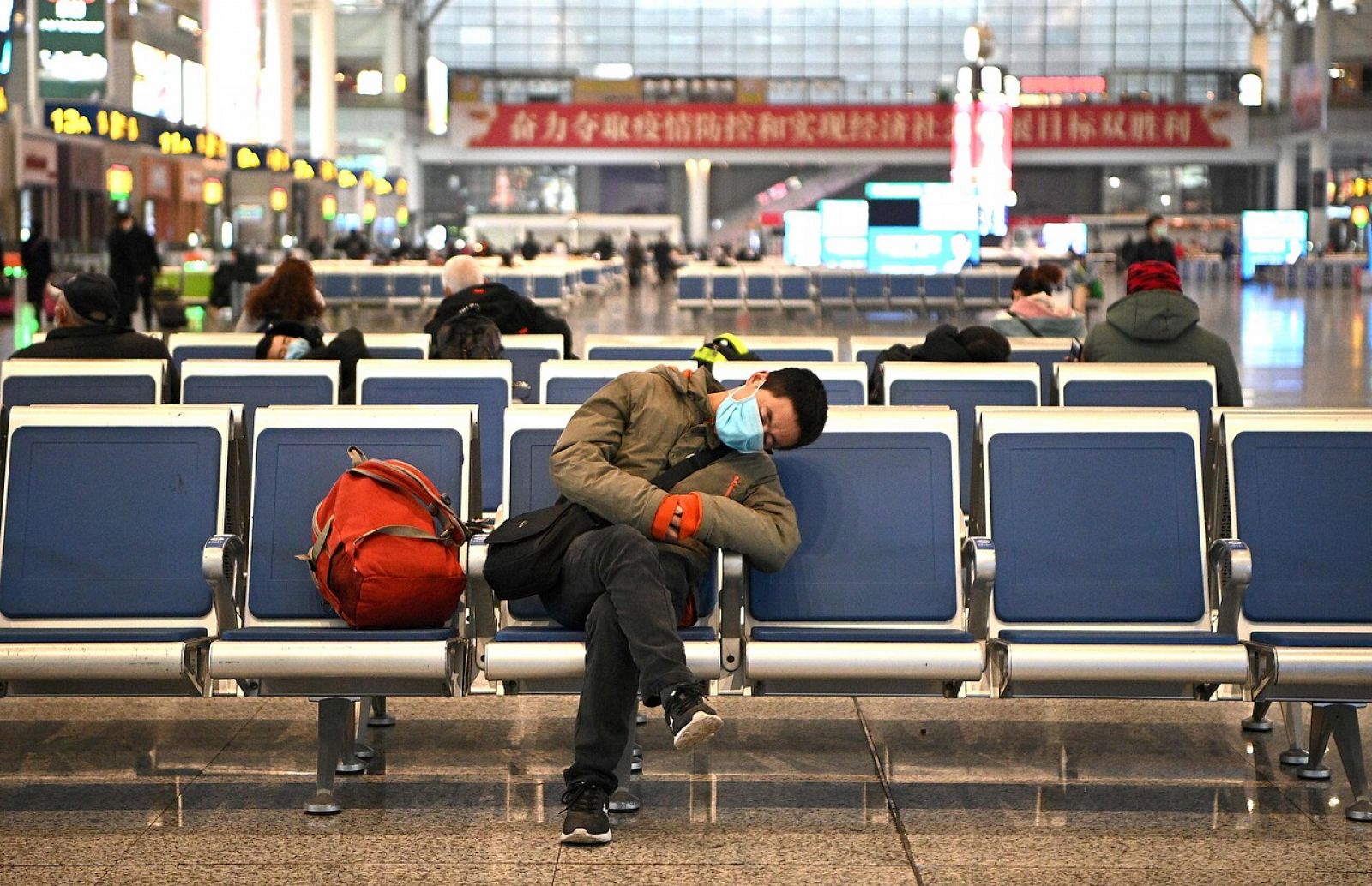 Un hombre duerme en la estación de Shangai con una mascarilla