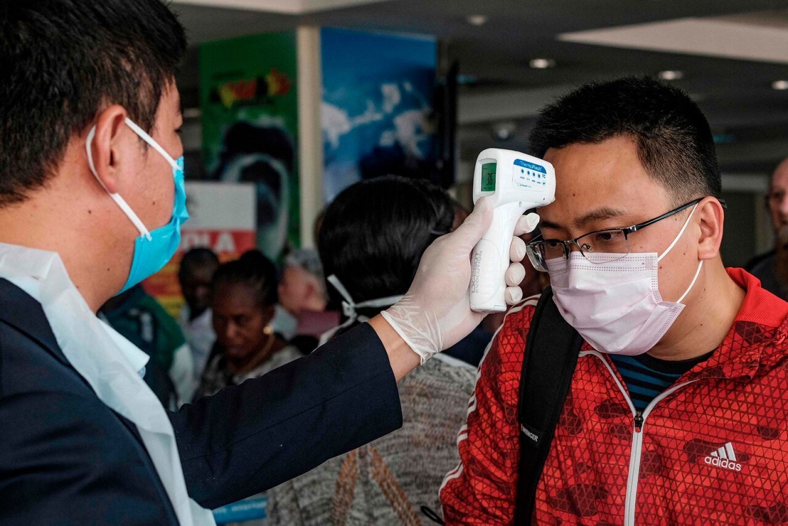 Un pasajero chino se toma la temperatura en un aeropuerto