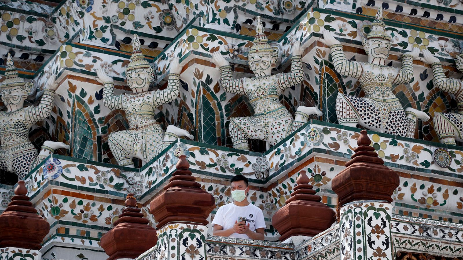 Un turista chino visita el Templo del Amanecer (Wat Arun) de Bangkok portando una mascarilla