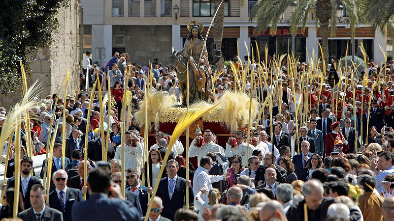 La imagen de "la burrita" rodeada de palmas blancas durante el recorrido oficial de la procesión del Domingo de Ramos en Elche. 