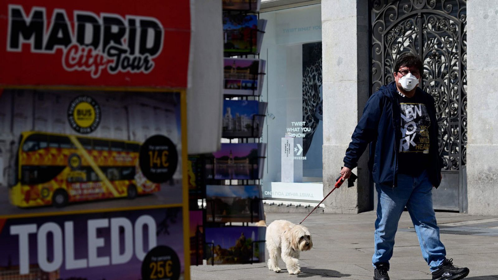 Imagen de un hombre llevando una mascarilla paseando a su perro por una calle de Madrid.