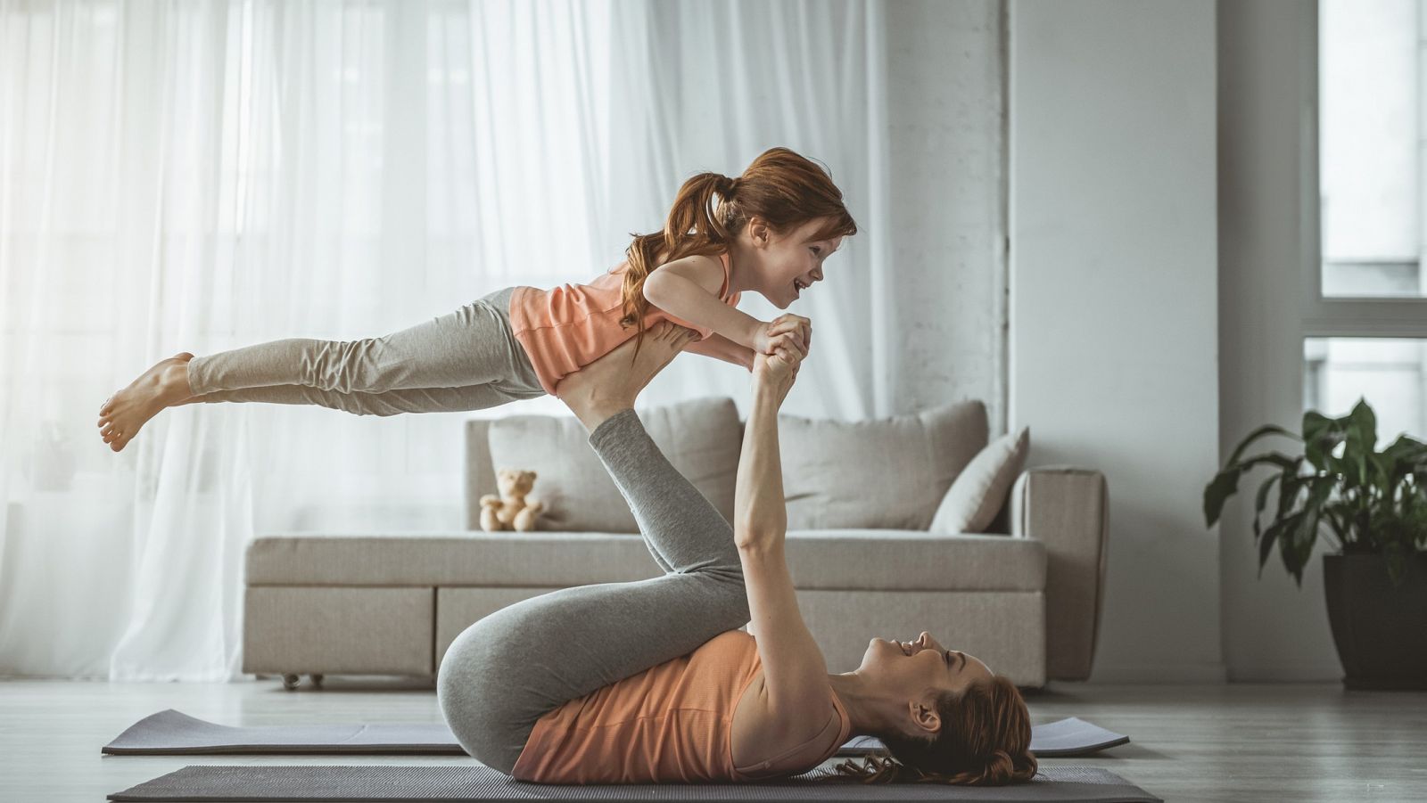 Una madre hace una rutina de gimnasia con su hija.