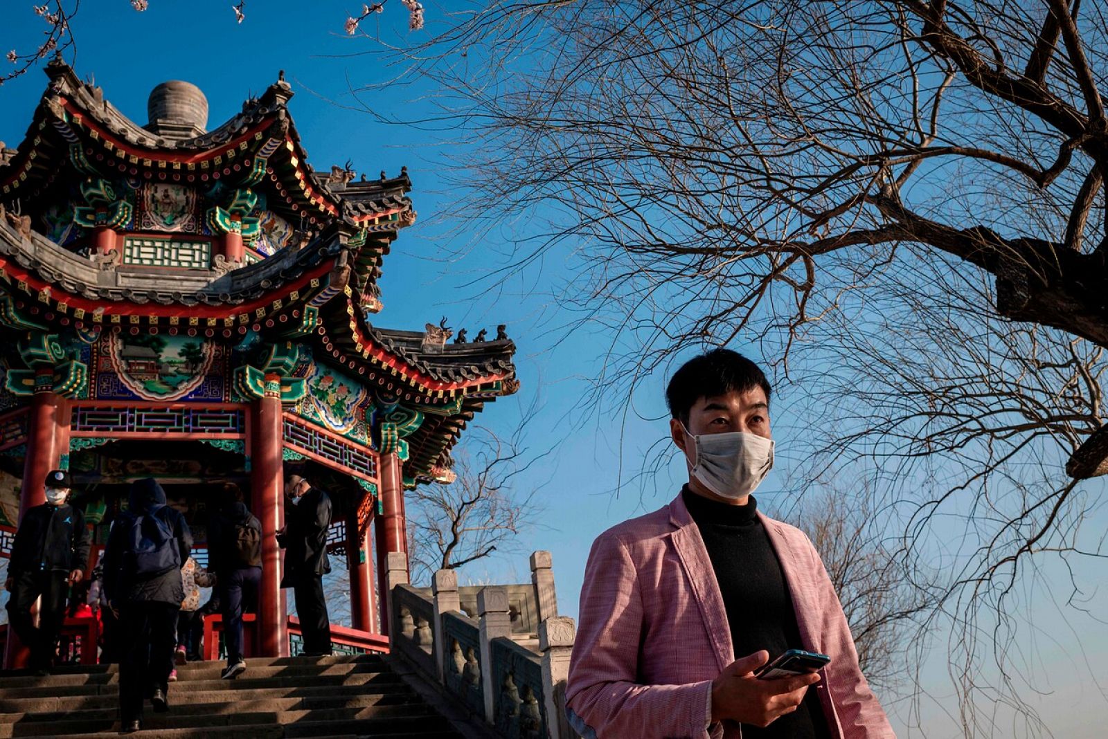 Un hombre con mascarilla camina ante el Palacio de Verano de Pekín