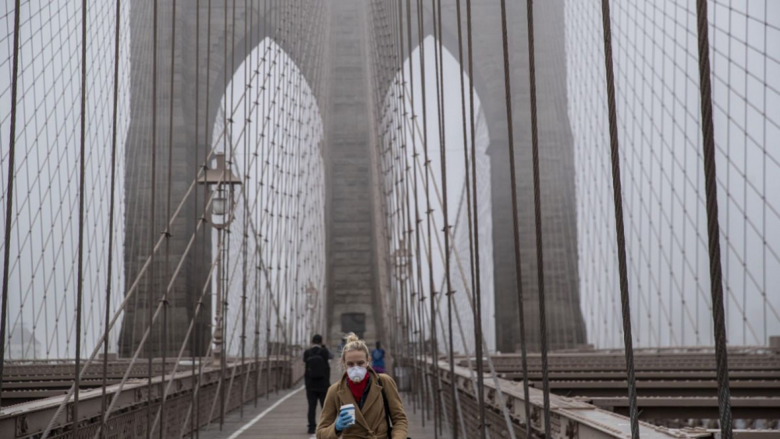 Una mujer con mascarilla andando por el puente de Brooklyn en Nueva York.