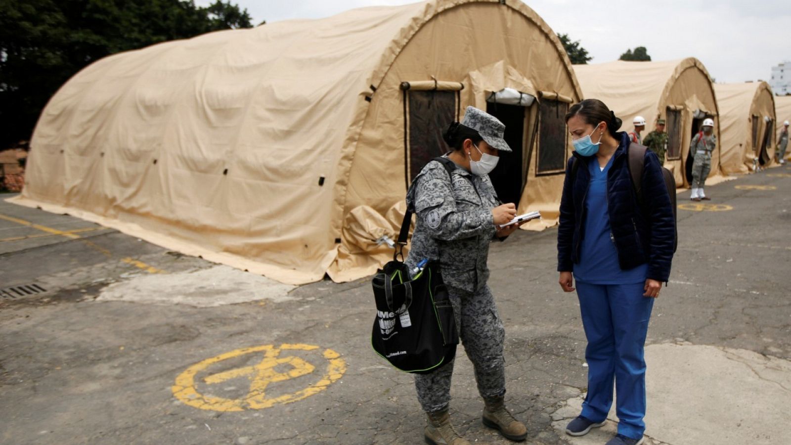 Una soldado y una enfermera en el exterior de una carpa que se está construyendo en Bogotá
