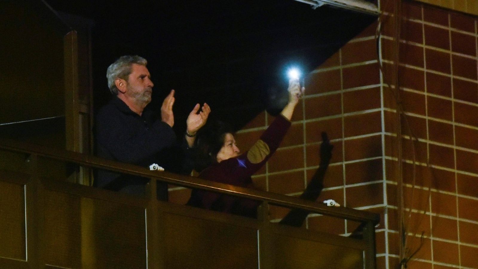 Vecinos del Hospital de Cruces, en Barakaldo (Bizkaia), aplauden y utilizan la linterna del móvil desde sus balcones