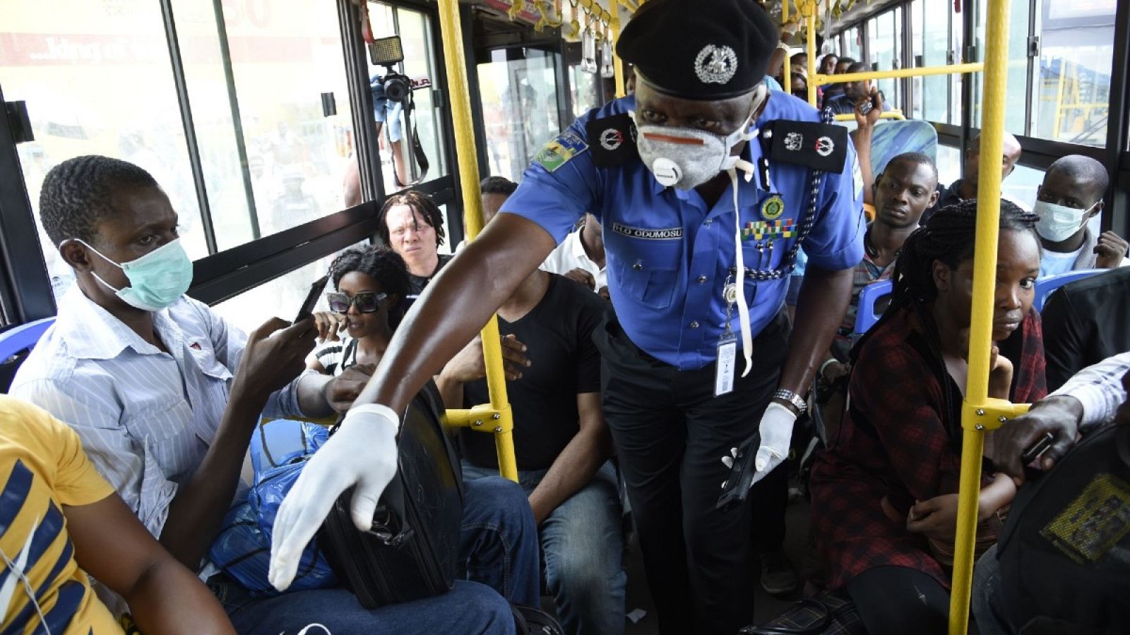 Policía nigeriano supervisando la distancia entre pasajeros por el coronavirus