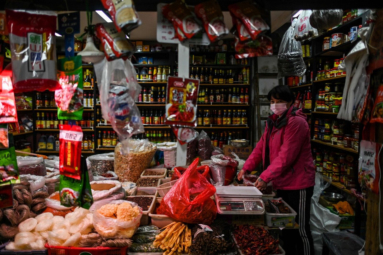 Una vendedora asiste su tienda en un mercado de Wuhan, China