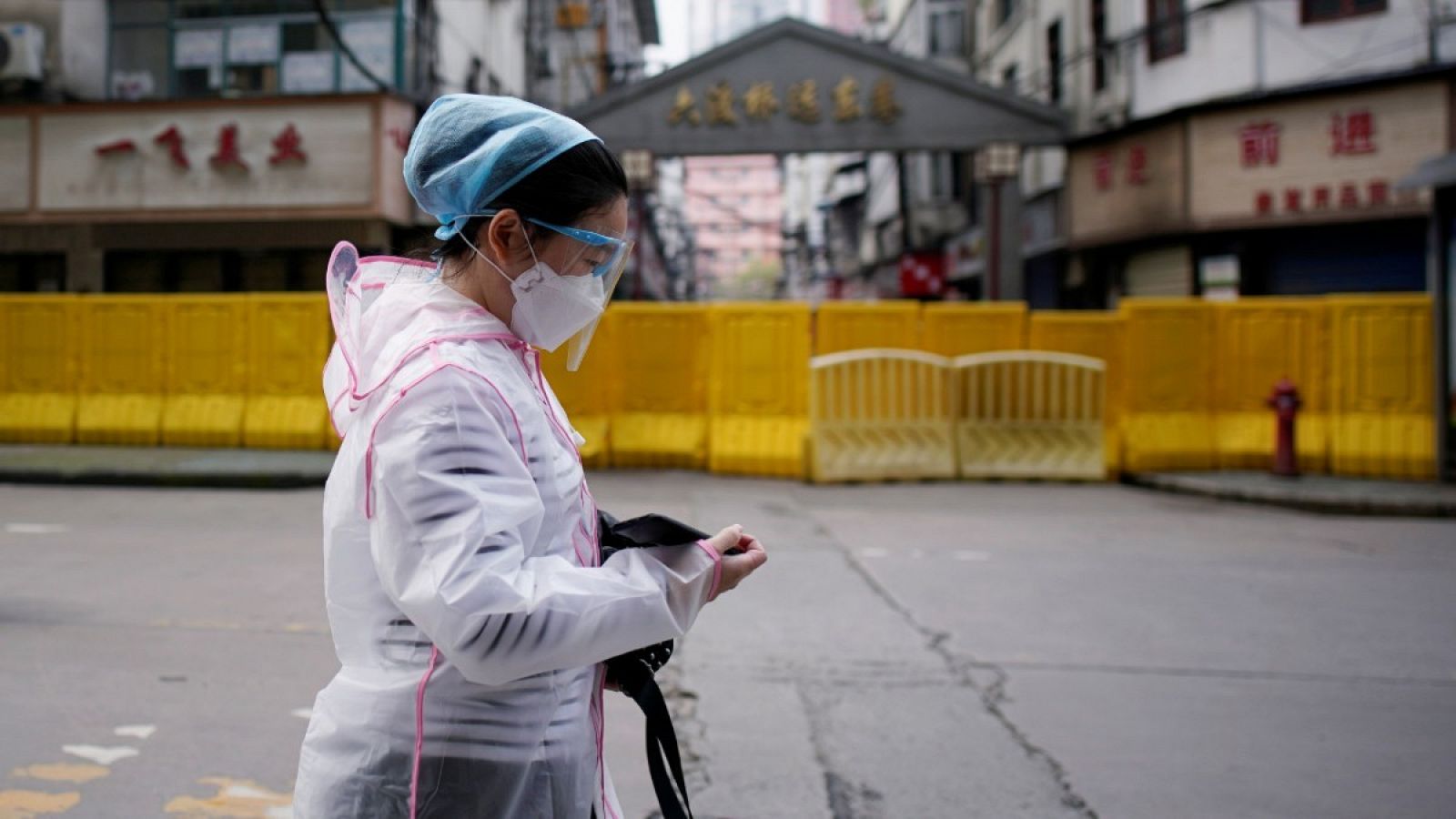 Una mujer con mascarilla caminando por una zona residencial en Wuhan, China. 