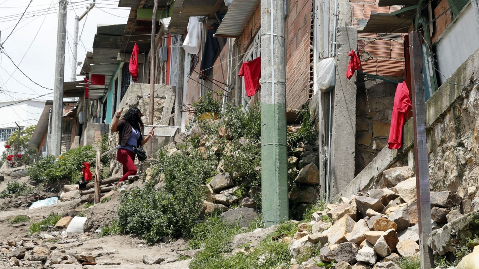 Una niña quita una trapo rojo de su ventana, símbolo con el que se identifican las familias que necesitan comida durante la cuarentena en Soacha (Colombia)