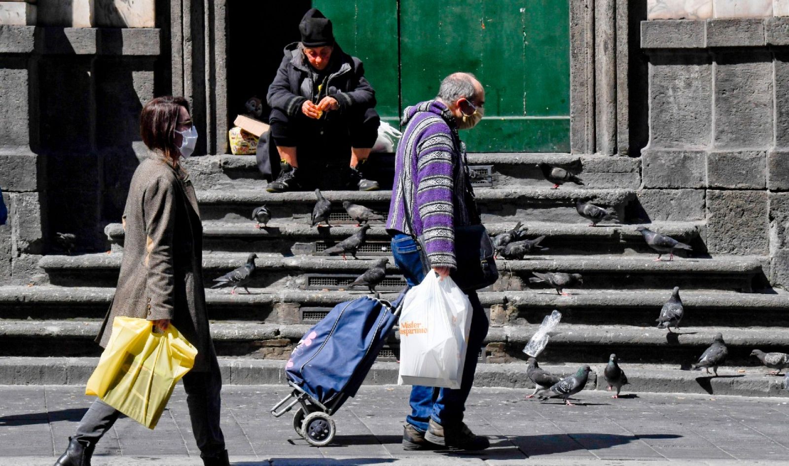 Una mujer sin hogar ni protección contra el coronavirus alimenta a las palomas en Nápoles