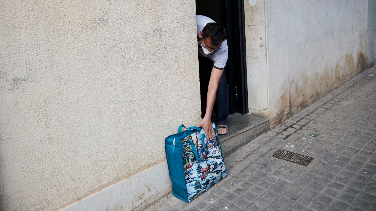 Una persona recoge el lote que voluntarios de la Cruz Roja le han entregado durante el reparto urgente de alimentos en Barcelona.