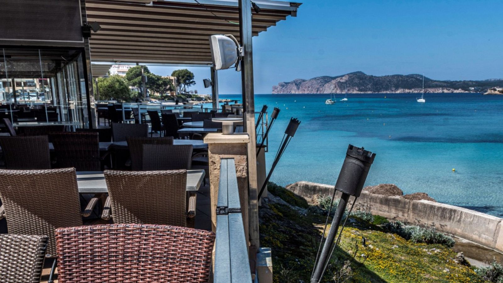 Terraza de un restaurante cerrado con vistas a una playa de Baleares.