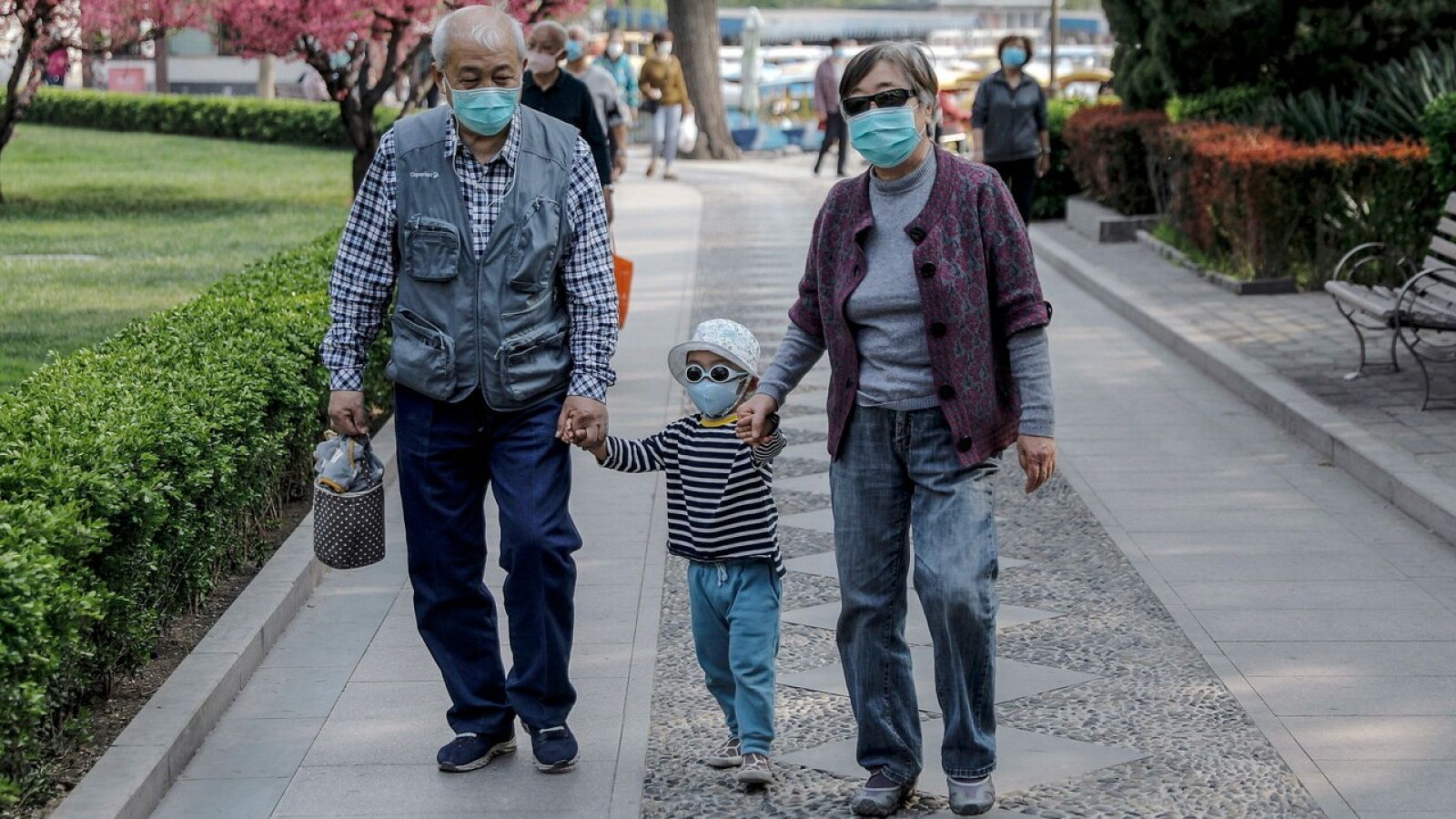 Una familia pasea por un parque de Pekín llevando mascarillas