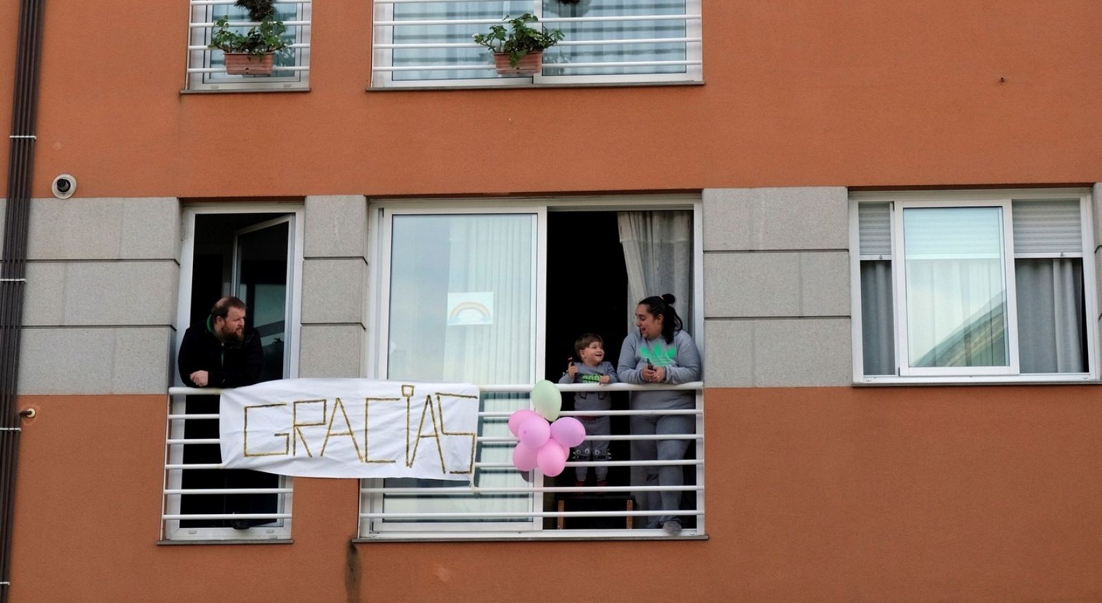 Un niño se asoma a la ventana en Narón (A Coruña) para ver un desfile organizado por Bomberos y Policía Local para dar "un aplauso para los niños y niñas" del pueblo.