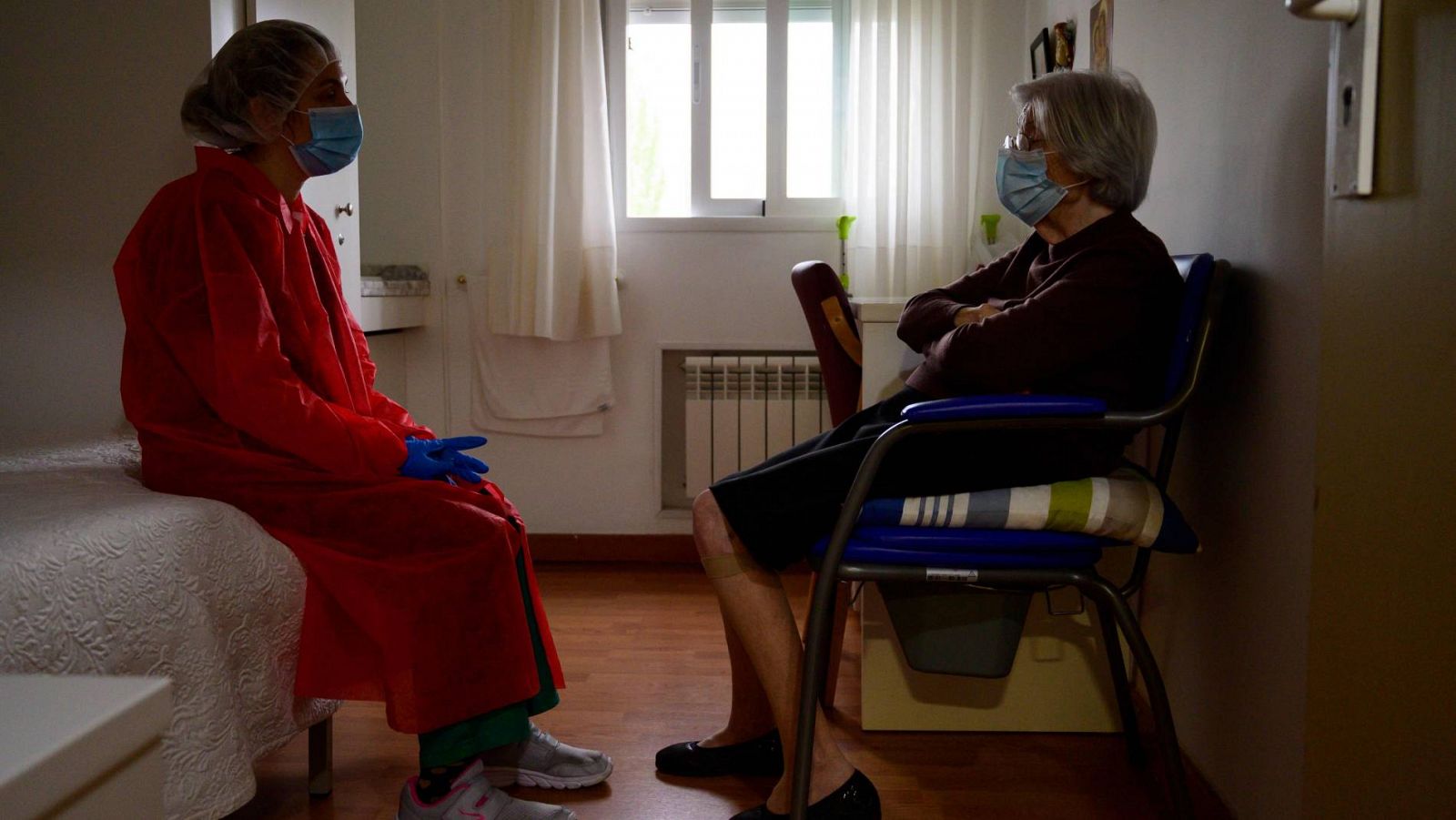 Una trabajadora de la residencia Las Praderas, en Pozuelo de Alarcón, charla con una de las internas, ambas ataviadas con mascarillas para protegerse del coronavirus