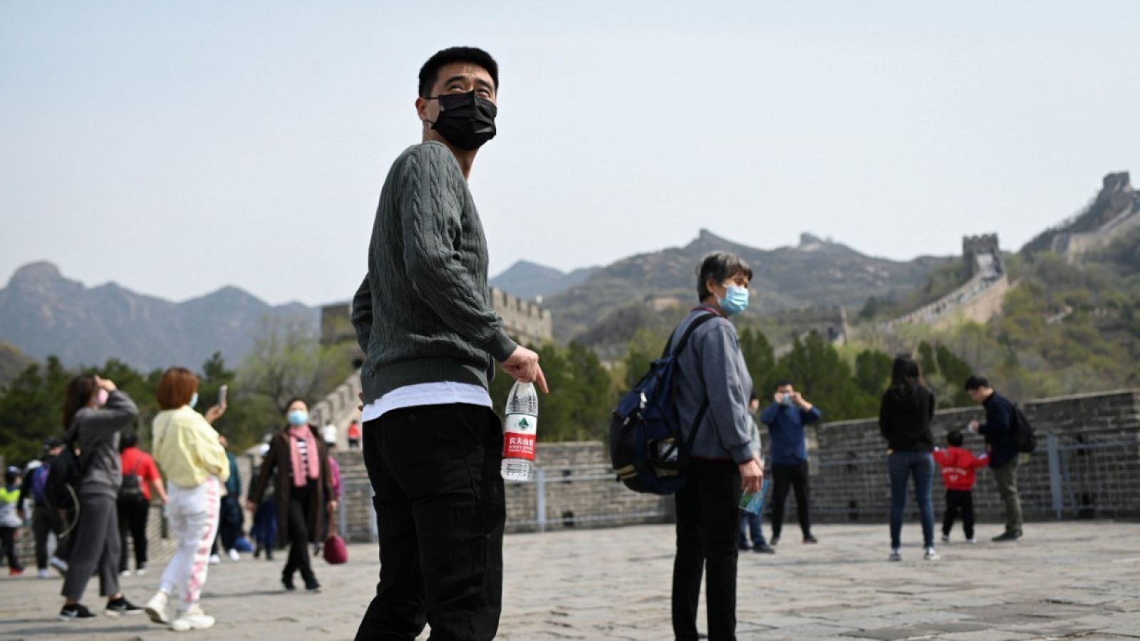 Gente usando mascarillas mientras visitan la Gran Muralla China en Pekín.