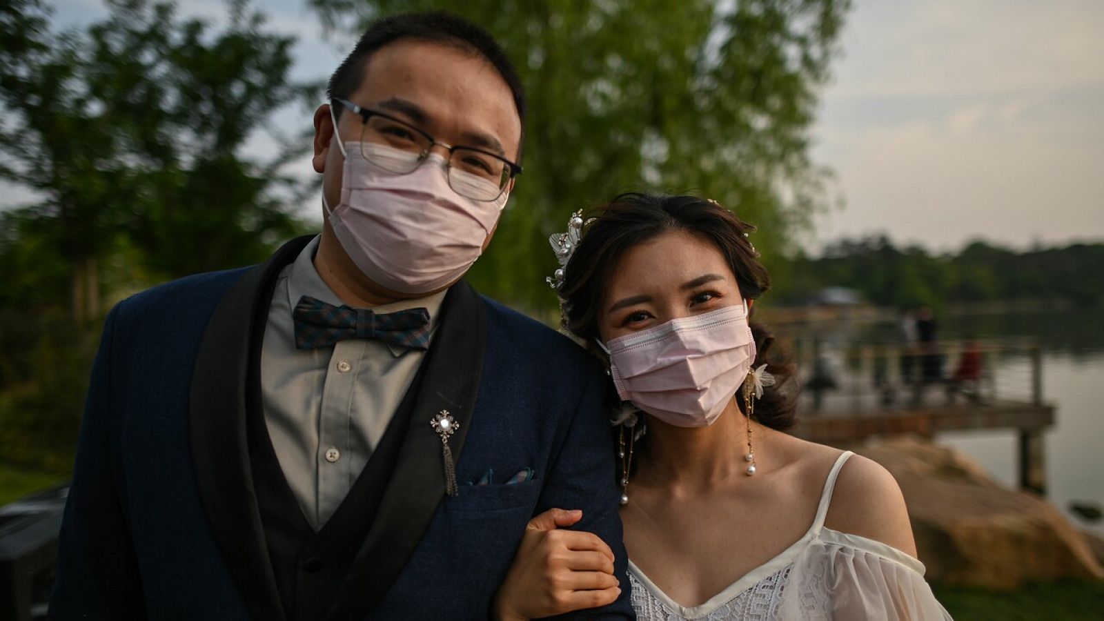 Una pareja sonríe bajo las mascarillas durante una sesión de fotos en Wuhan