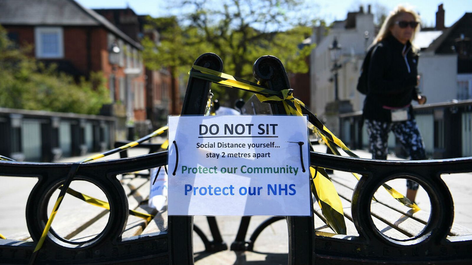 Bancos fuera de los límites en Windsor, en Inglaterra, donde un cartel recuerda la norma de distancia social para contener el virus.