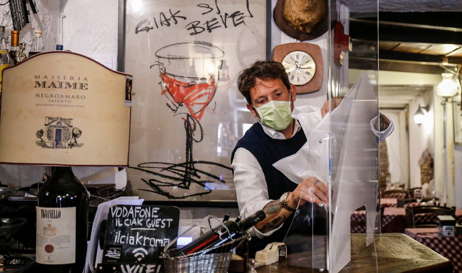 Un camarero prepara unas mamparas contra el coronavirus en un restaurante de Roma