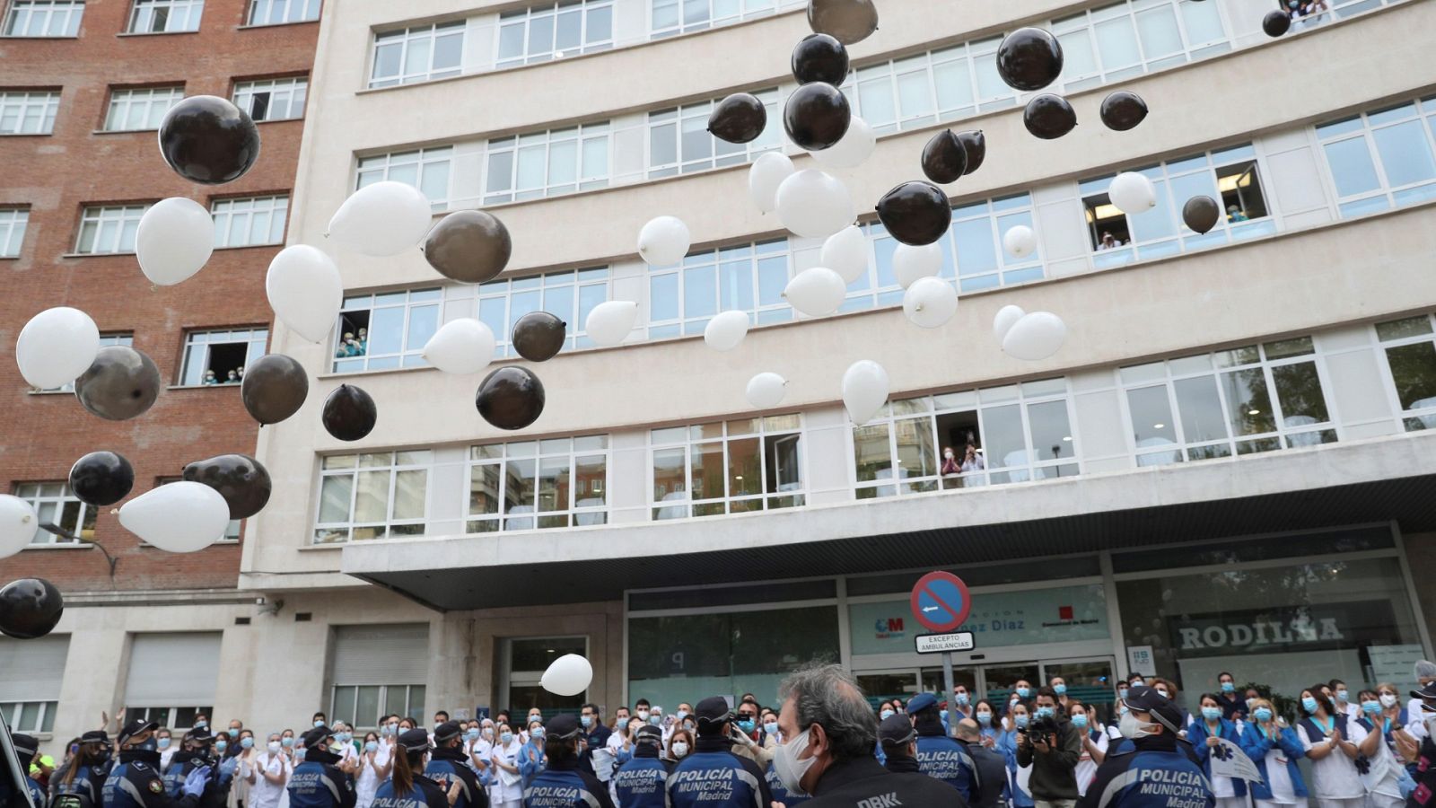 Agentes de la Policía Municipal de Madrid y sanitarios de la Fundación Jimenez Diaz rinden homenaje a las víctimas del Covid-19 soltando globos blancos y negros.