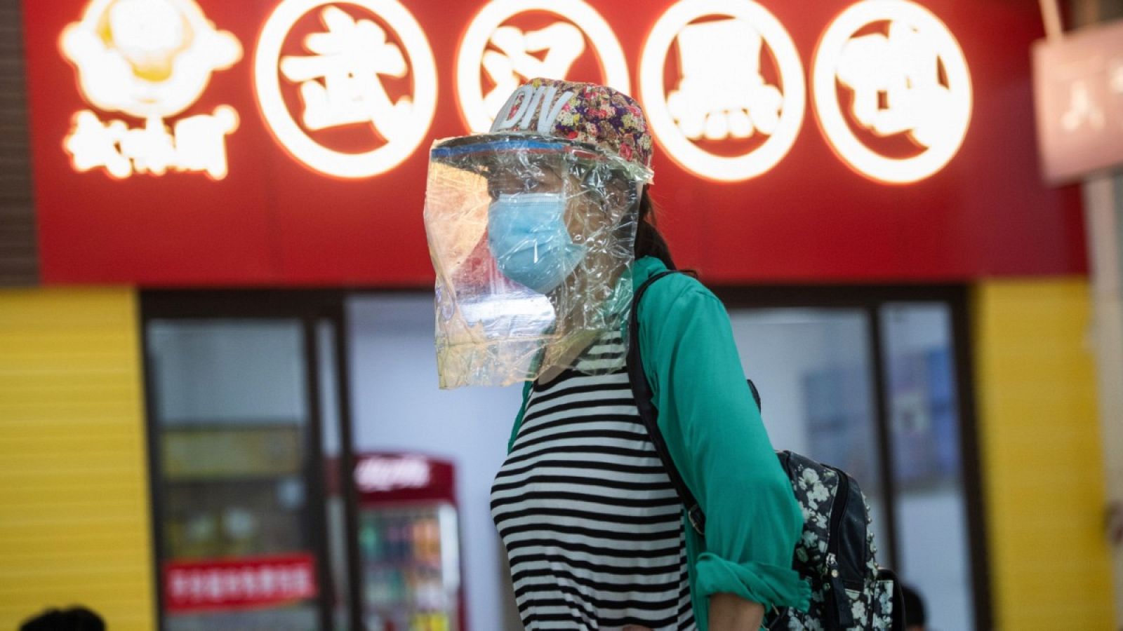 Una mujer con una pantalla protectora y con una mascarilla en una estación de autobuses de larga distancia en Wuhan, China.