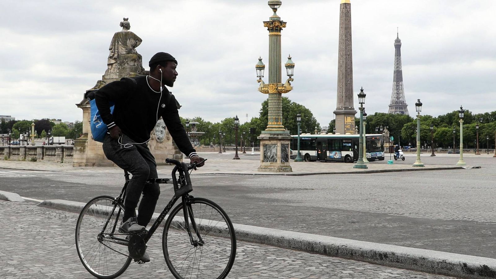 un ciclista con una mochila típica de reparto a domicilio, por el centro de París