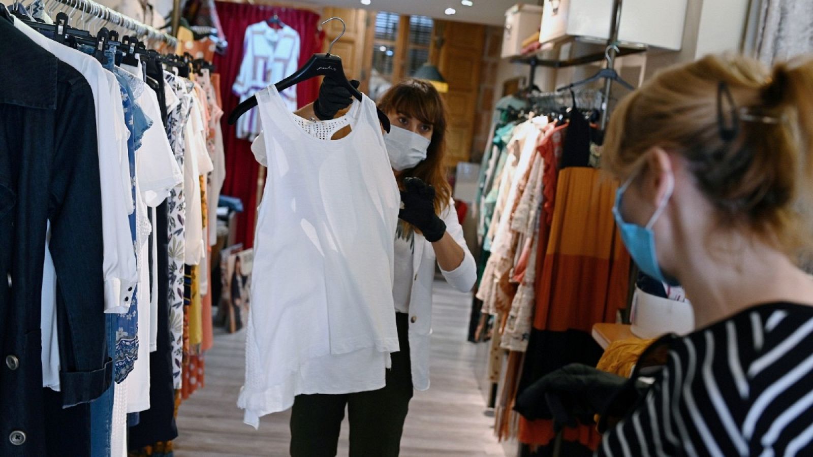Una trabajadora muestra ropa a una clienta en un comercio