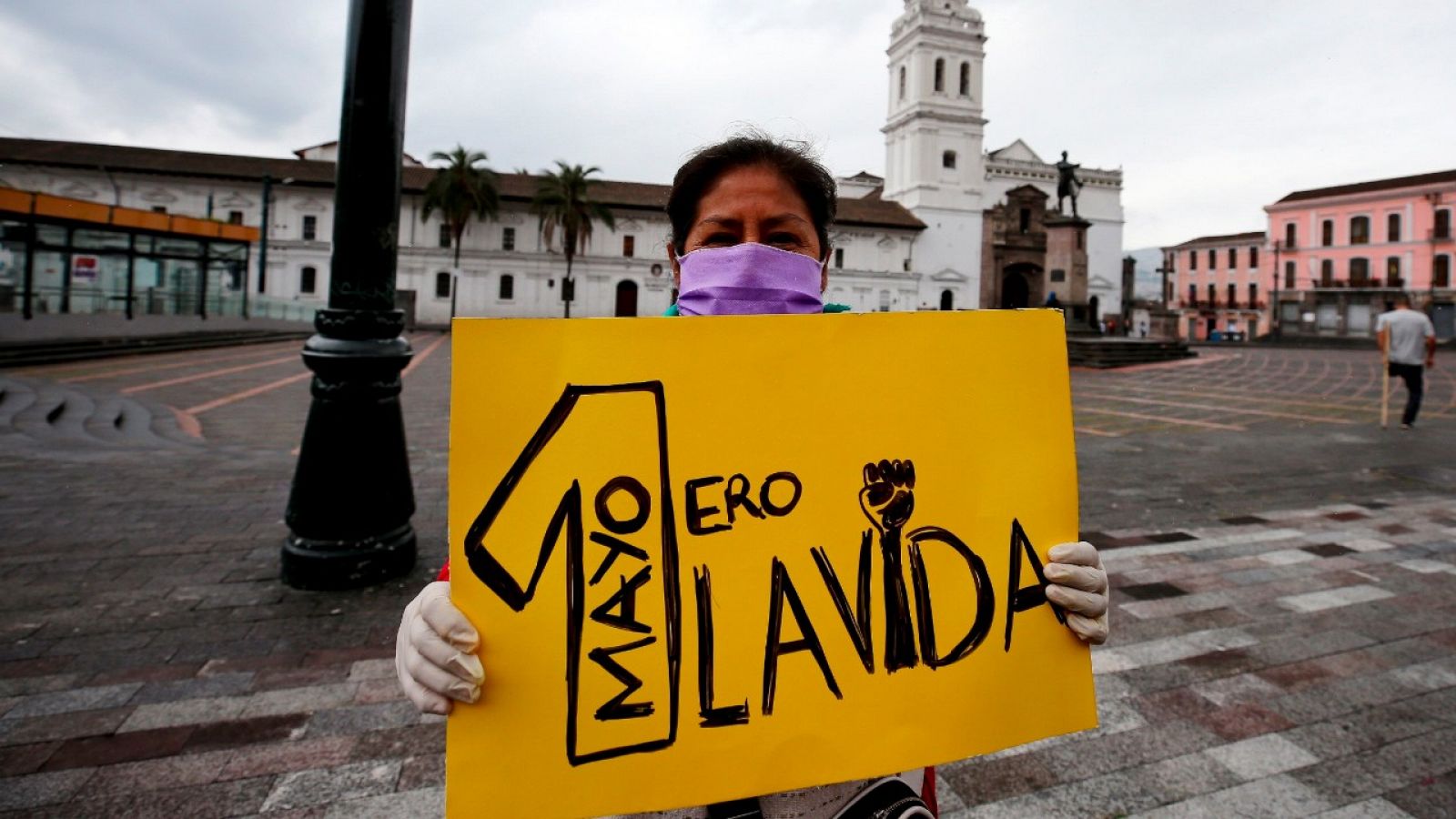 Una trabajadora muestra un cartel por el Día del Trabajo en Quito (Ecuador).