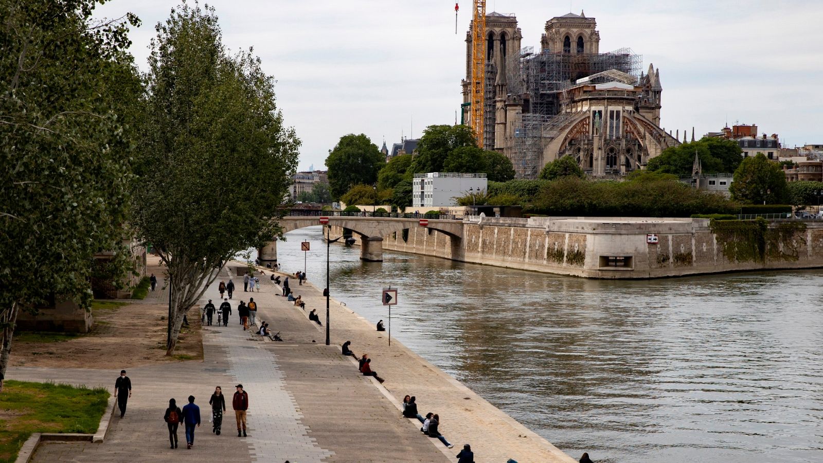 Varias personas pasean cerca del río Sena a su paso por la catedral de Notre Dame