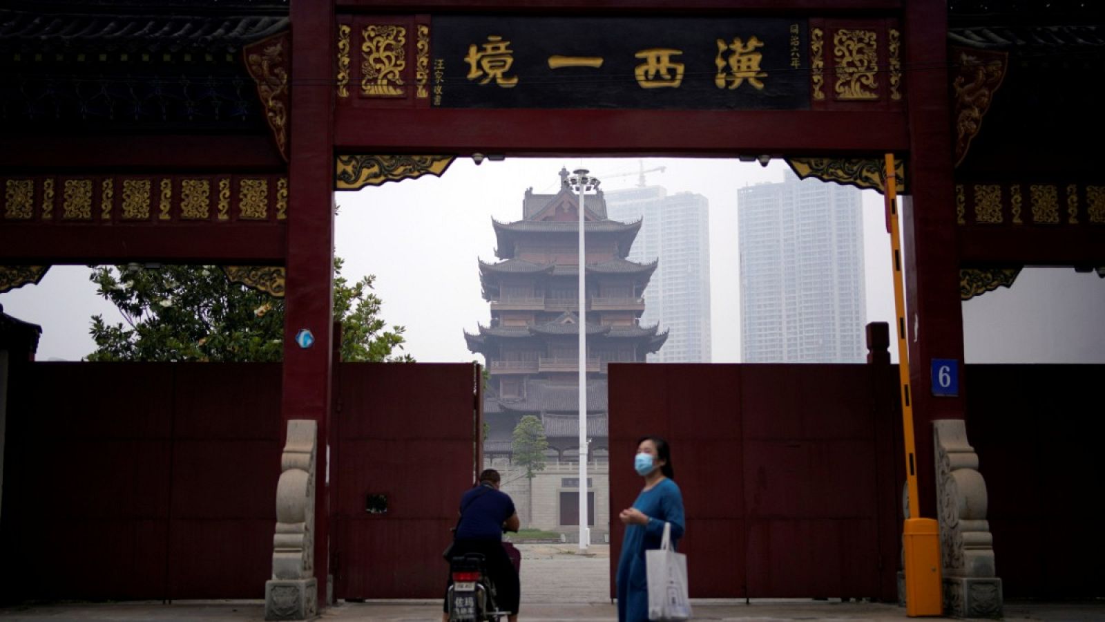 Una mujer con mascarilla caminando frente a un templo en Wuhan, China.