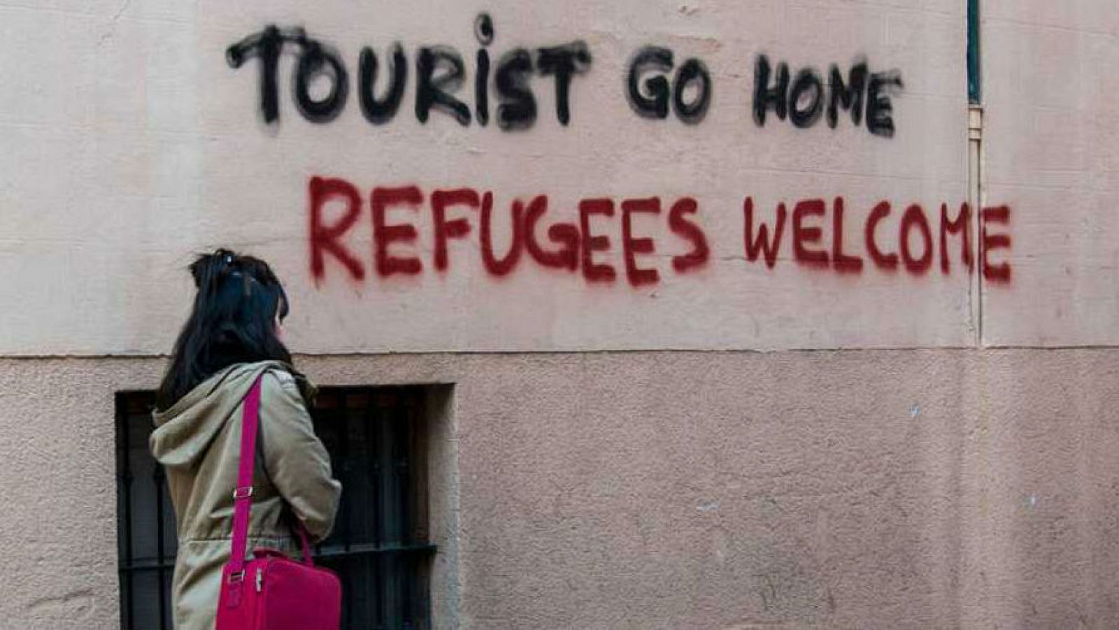 Imagen de archivo con una pintada en la que se puede leer "fuera turista" y "bienvenidos refugiados".