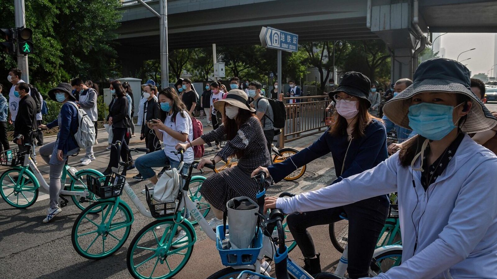 Ciudadanos chinos de camino al trabajo en bicicleta y con mascarillas