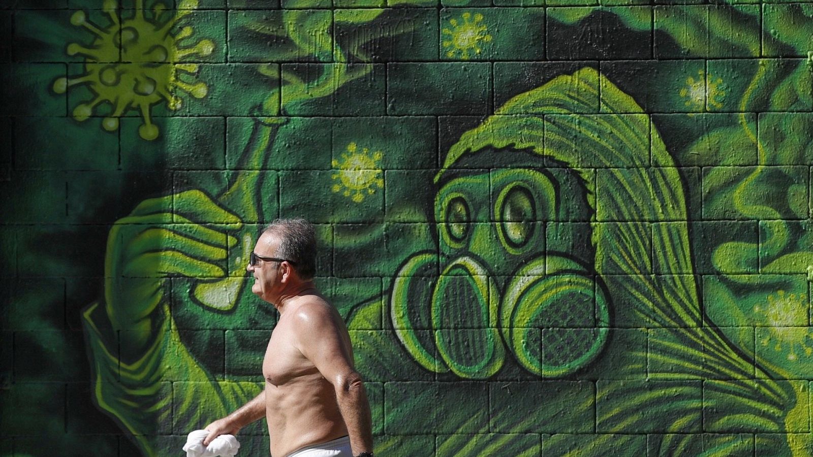 Un hombre camina ante un grafitti en una calle del centro de Barcelona este viernes