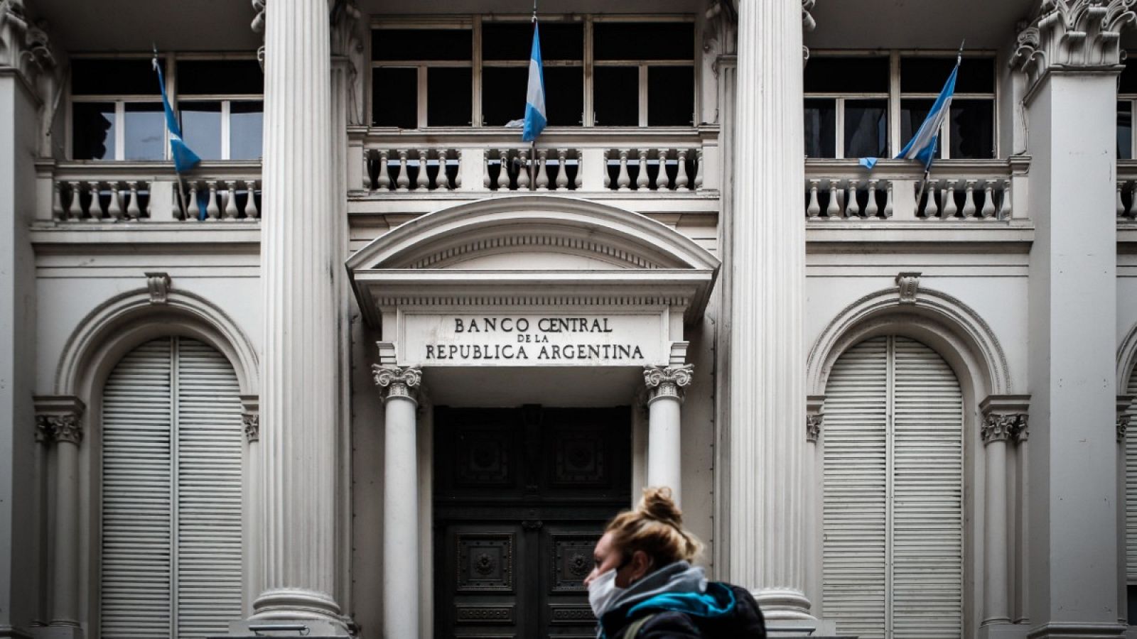 Una mujer con mascarilla caminando frente al Banco Central de Argentina en Buenos Aires.